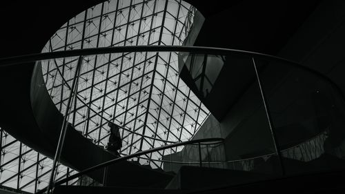 Free Silhouette of a person on a spiral staircase inside the iconic Louvre Pyramid in Paris, France. Stock Photo