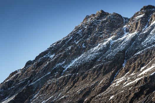 Stunning view of a rugged, snow-capped mountain peak in clear daylight.