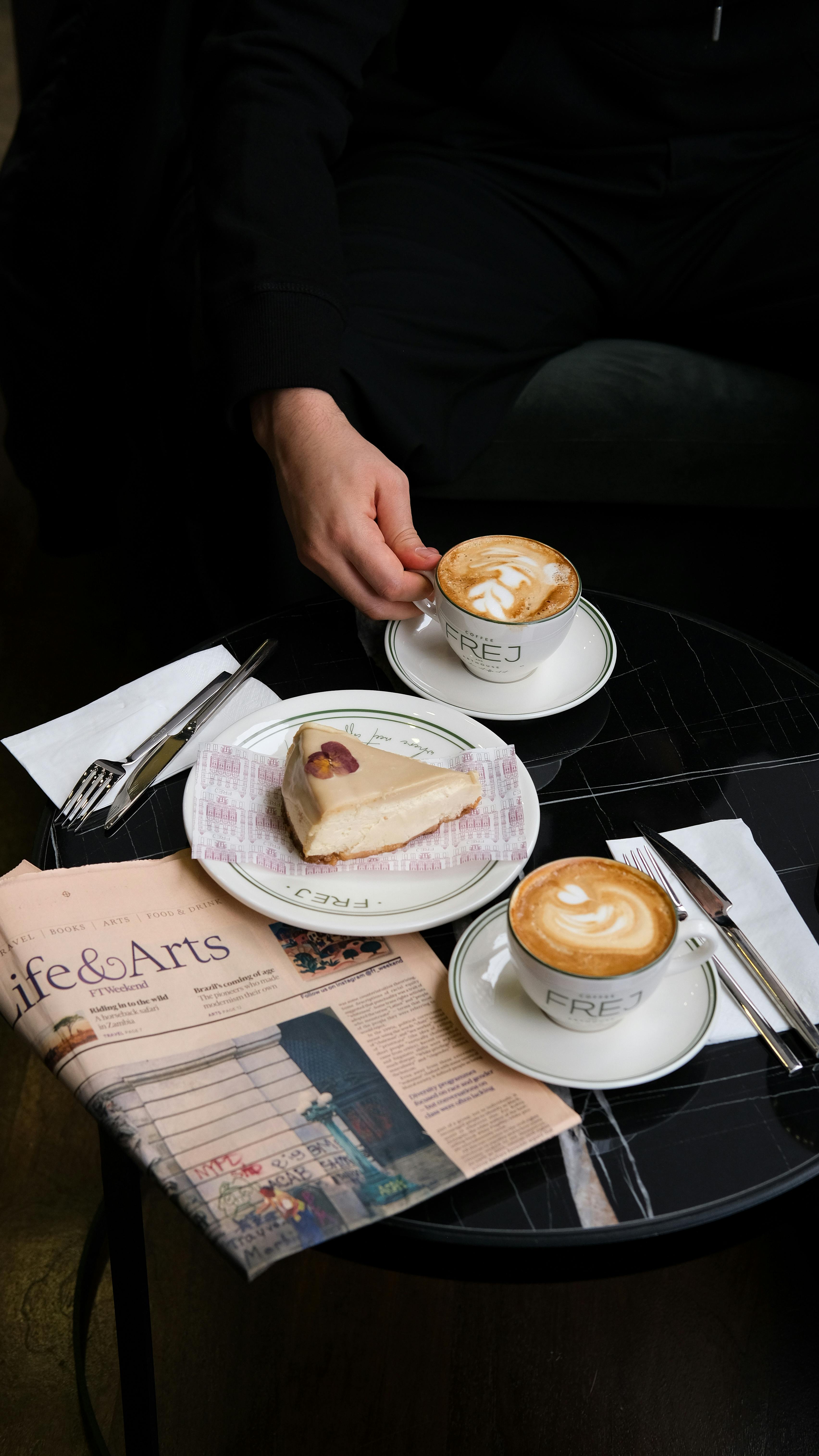 Cozy café setting with cappuccinos and dessert on a round table.