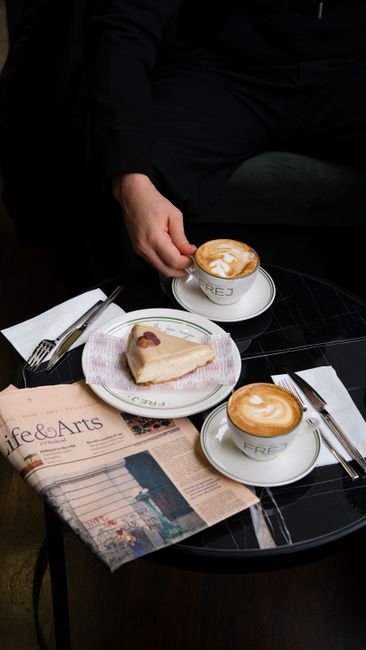 Cozy café setting with cappuccinos and dessert on a round table.