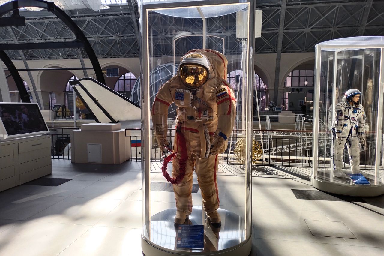 Historic space suits showcased in a museum with ample natural light.