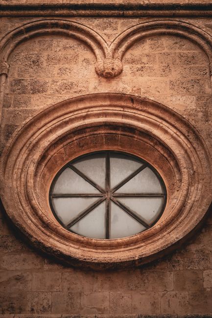Close-up of an ancient rose window on a historical building in Cagliari, Sardinia.