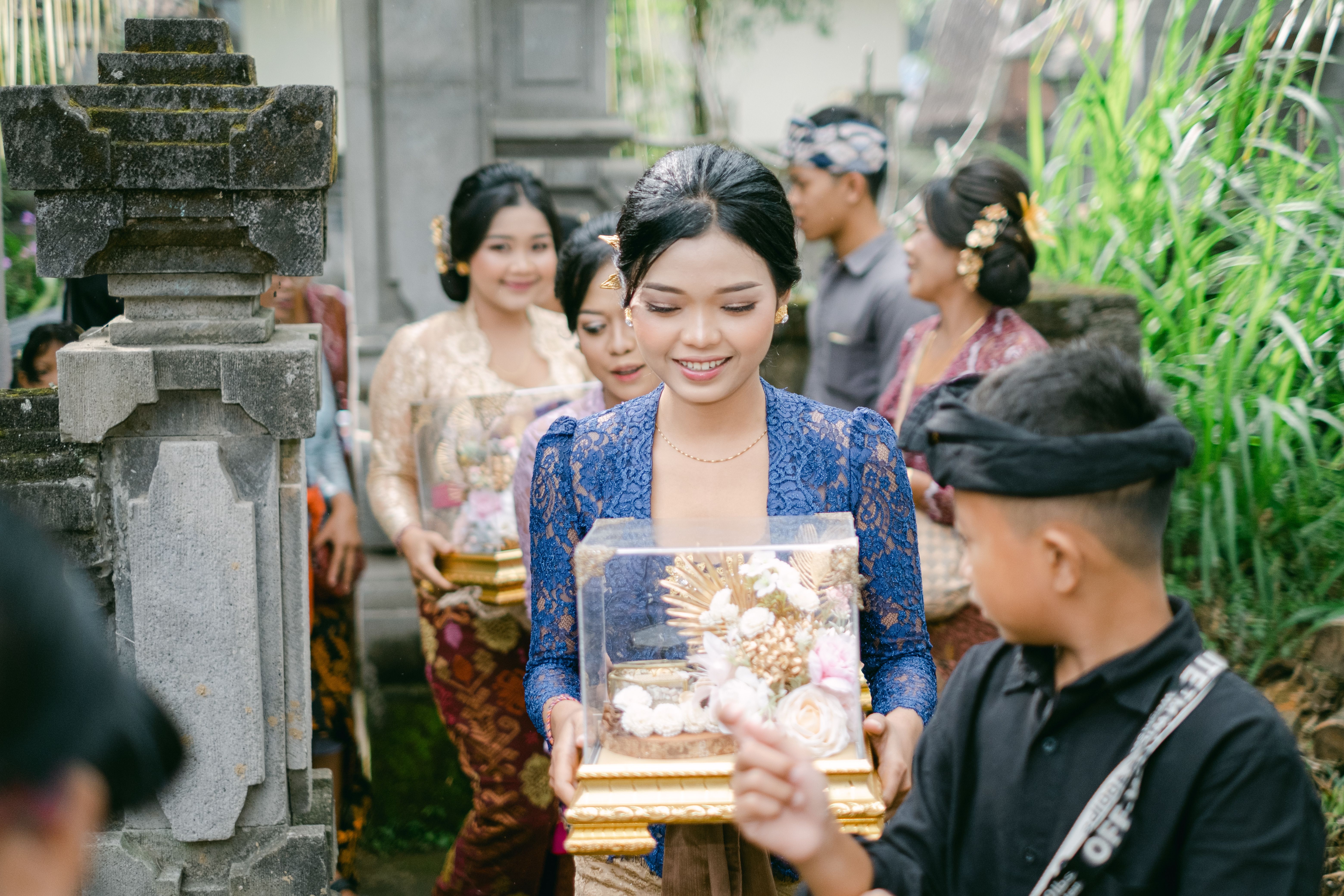 Balinese people in ceremonial attire participating in a traditional celebration, carrying a decorative gift tray.