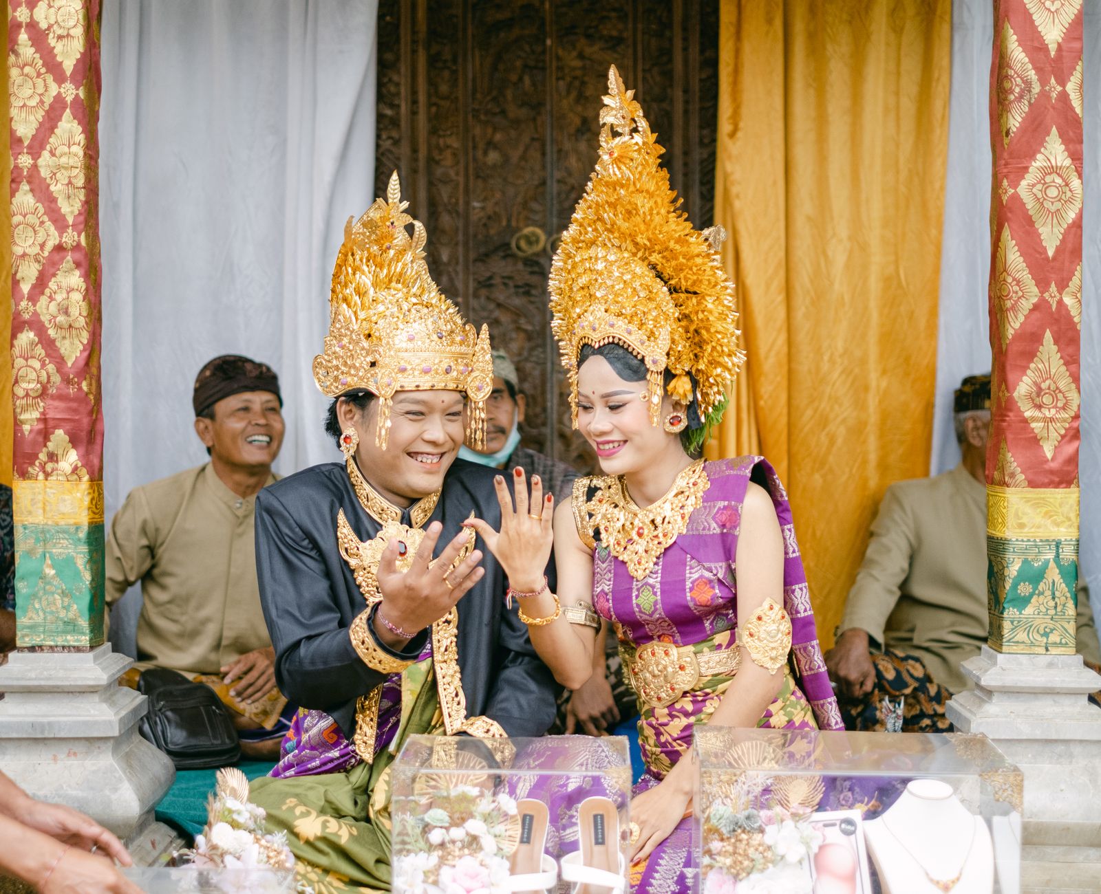 Balinese couple in traditional attire celebrating their wedding with joy and laughter.