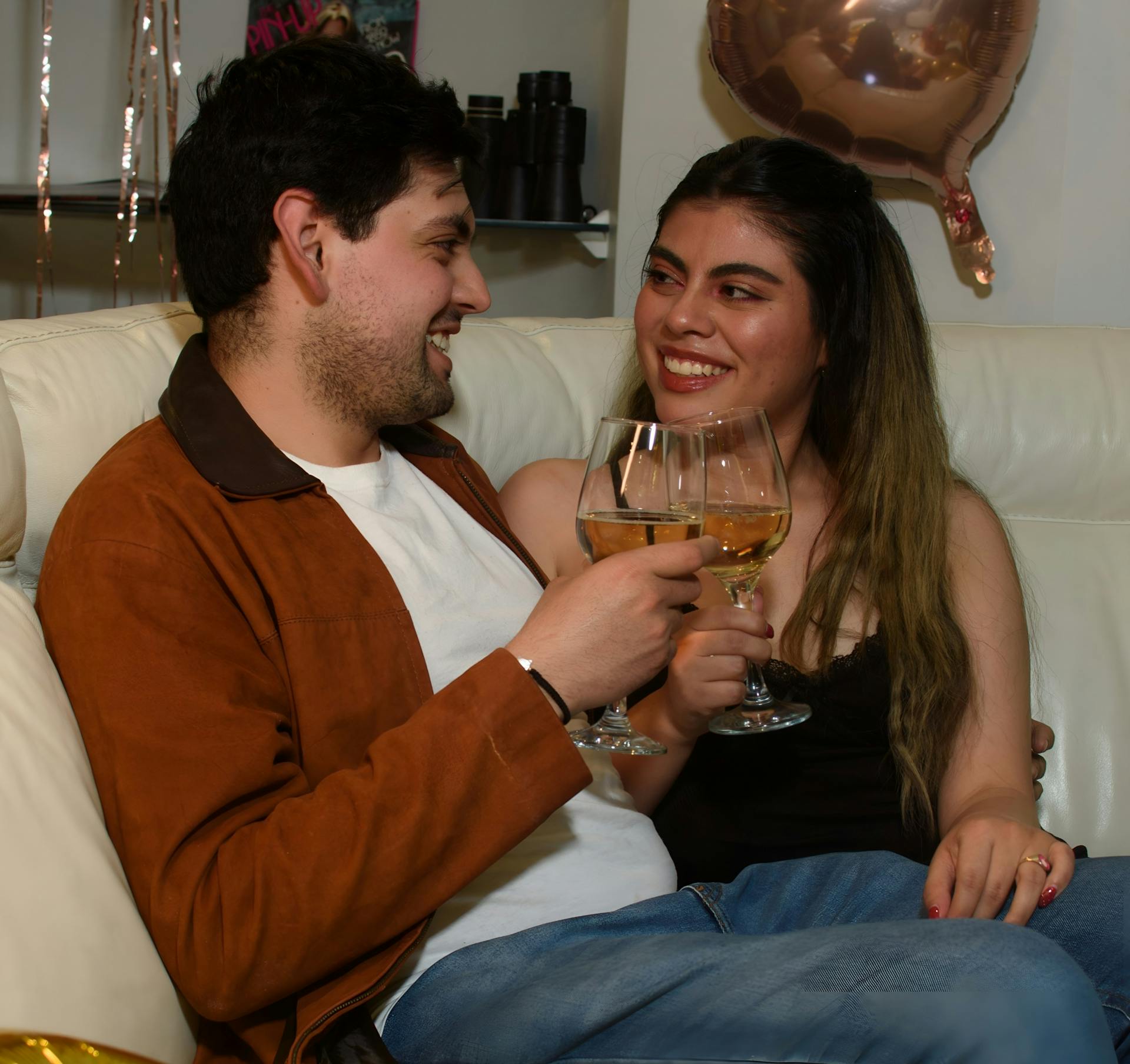 Happy couple toasting with wine glasses during a festive indoor celebration.