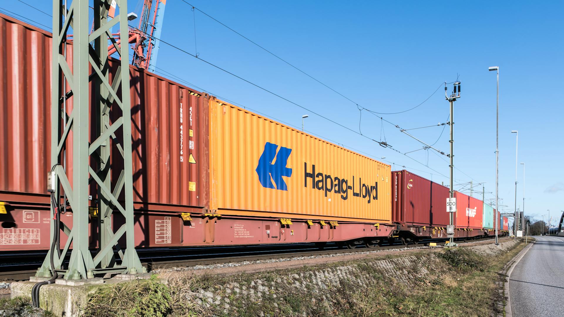 Freight train transporting containers near Hamburg harbor on a clear day.