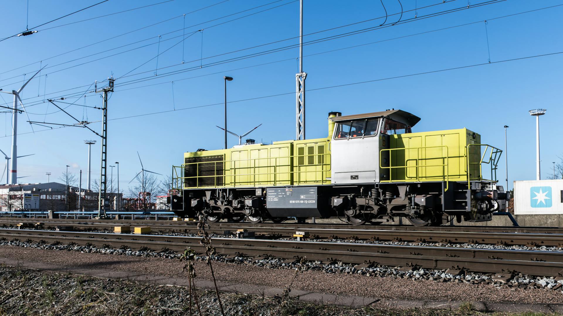 Freight train in Hamburg rail terminal with wind turbines and infrastructure.