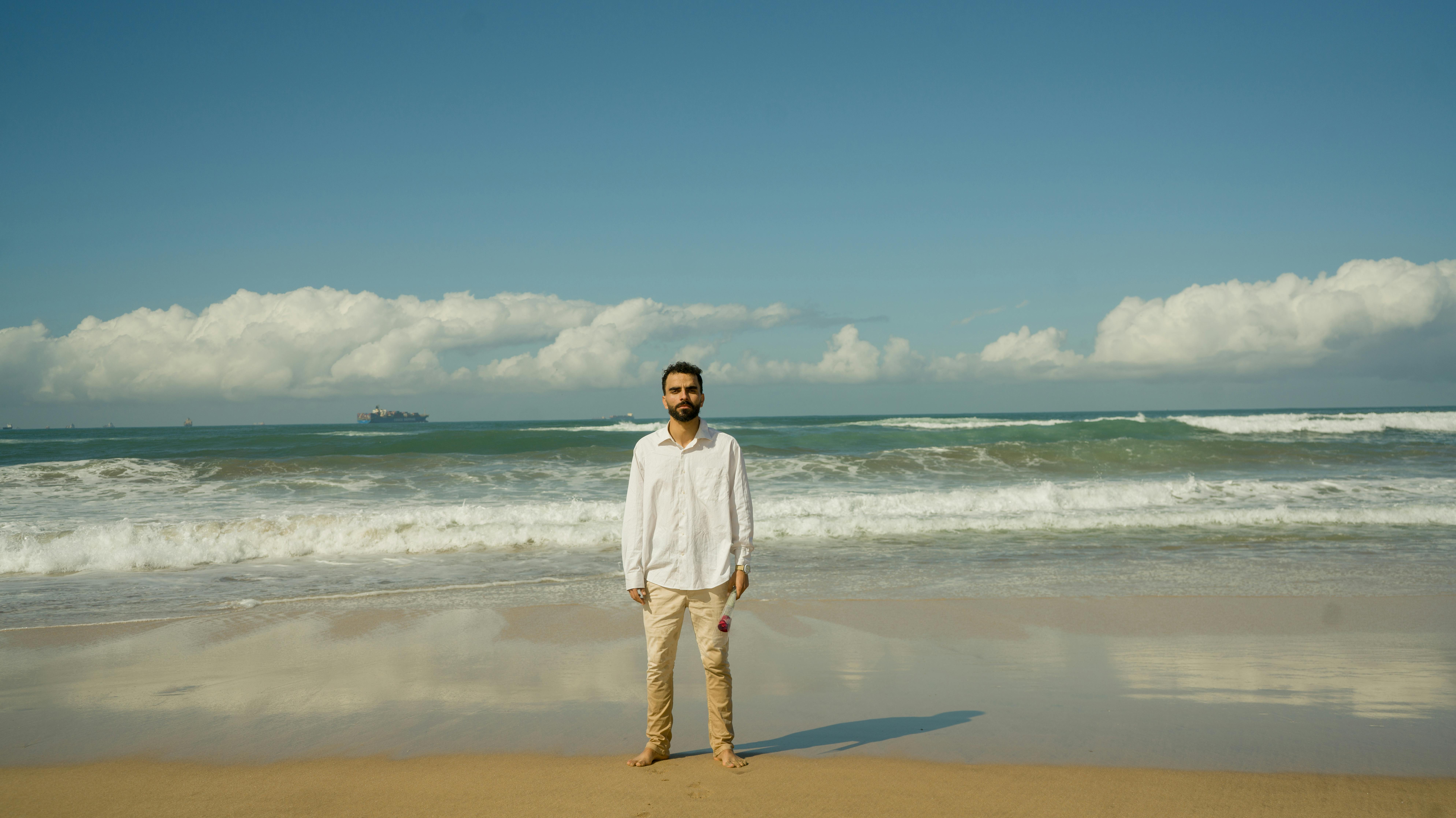 A solitary man stands on a sunny beach, capturing serenity and nature's beauty.