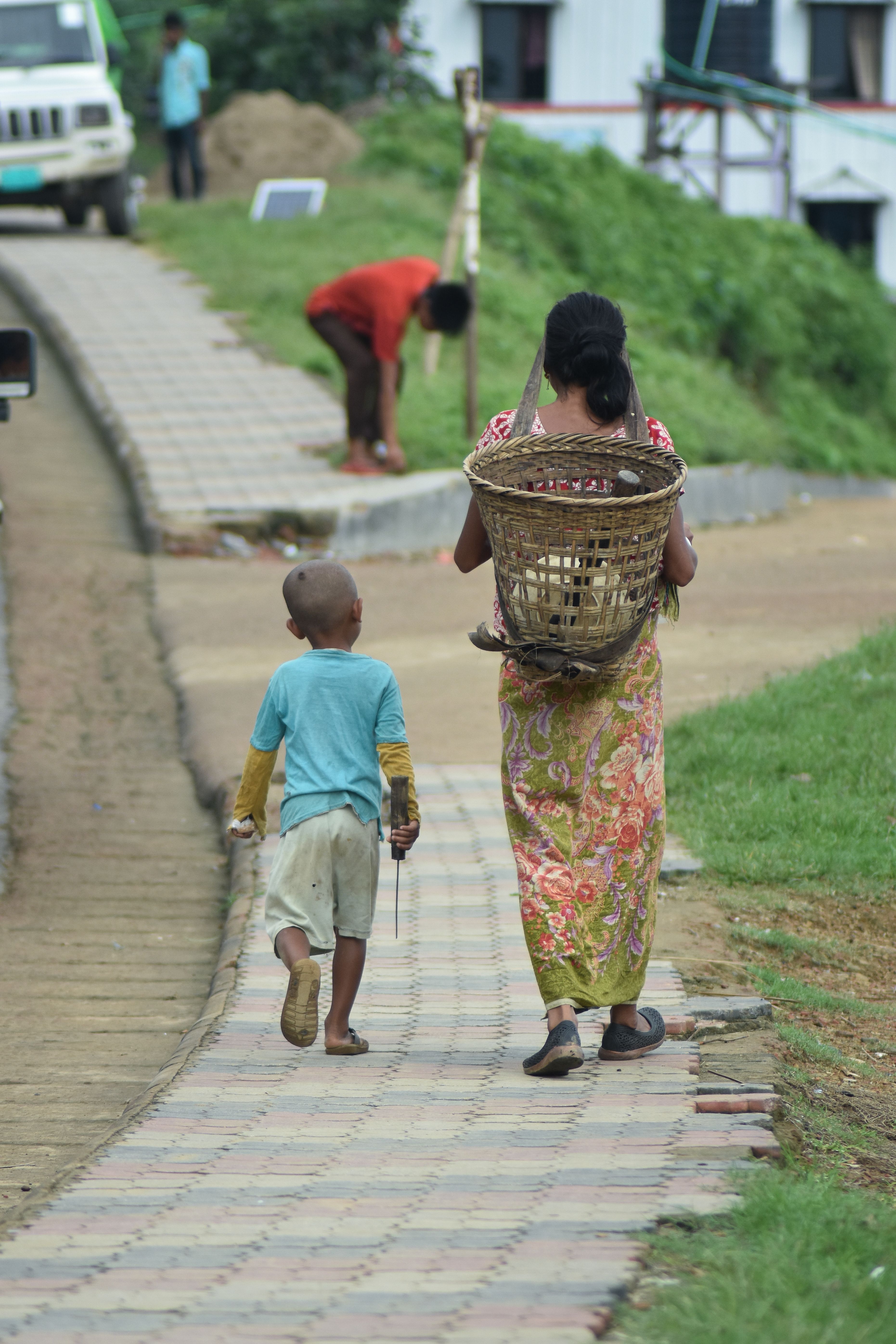A mother and child walk along a path in rural Bandarban, Bangladesh, showcasing daily village life.