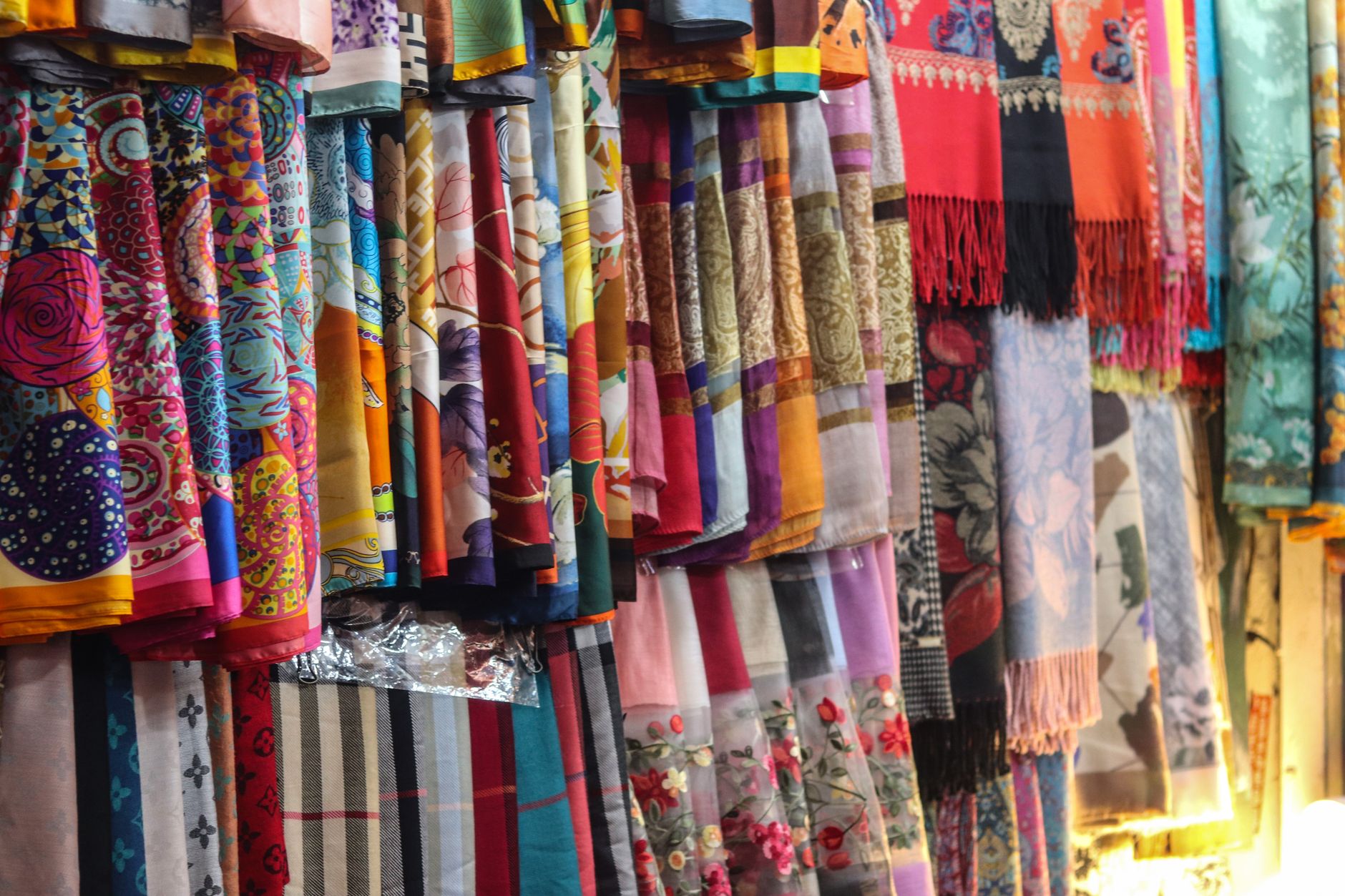 A vivid collection of silk shawls showcasing intricate patterns and bold colors on display.