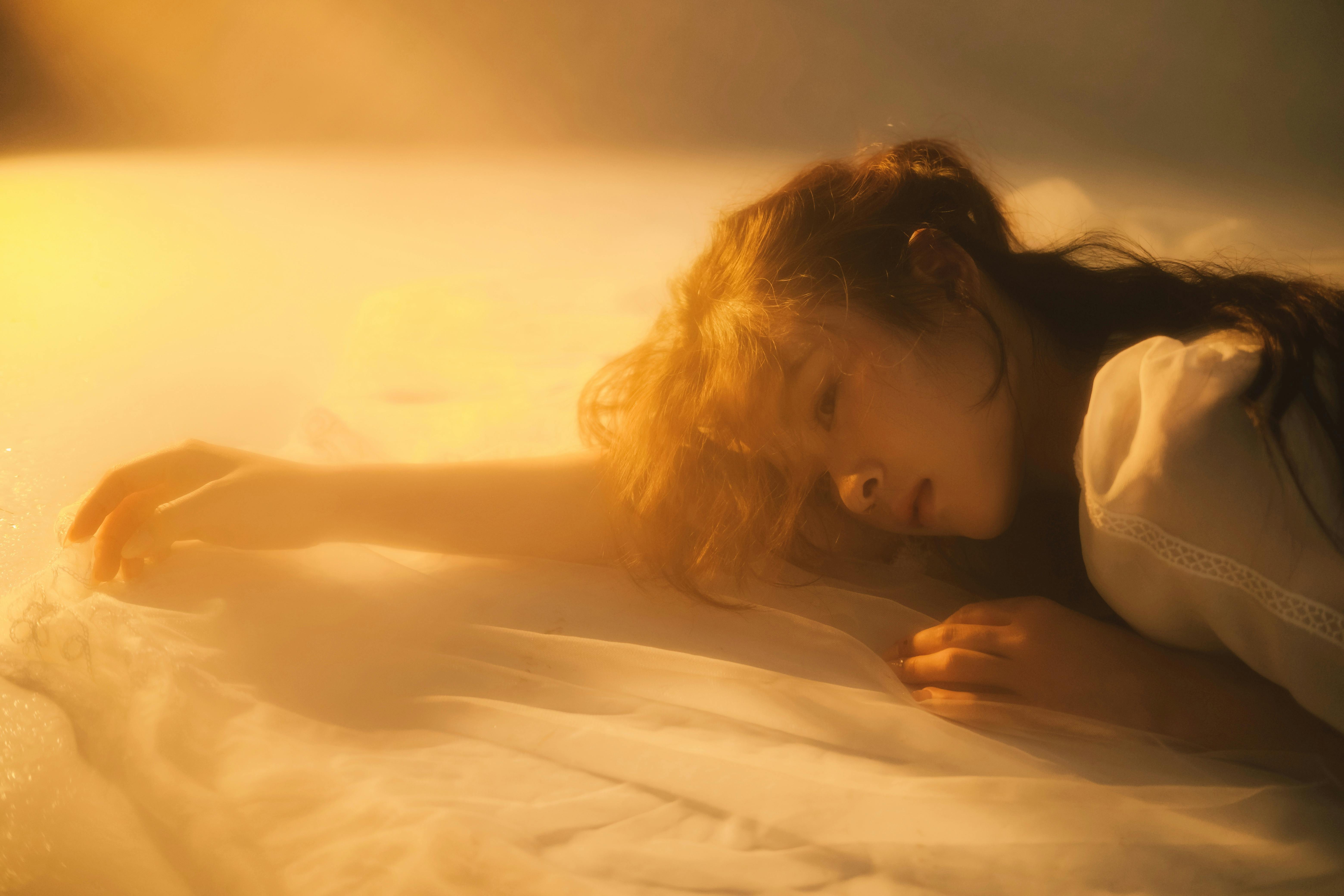 Dreamy woman resting peacefully in golden soft light, eyes closed in serene repose