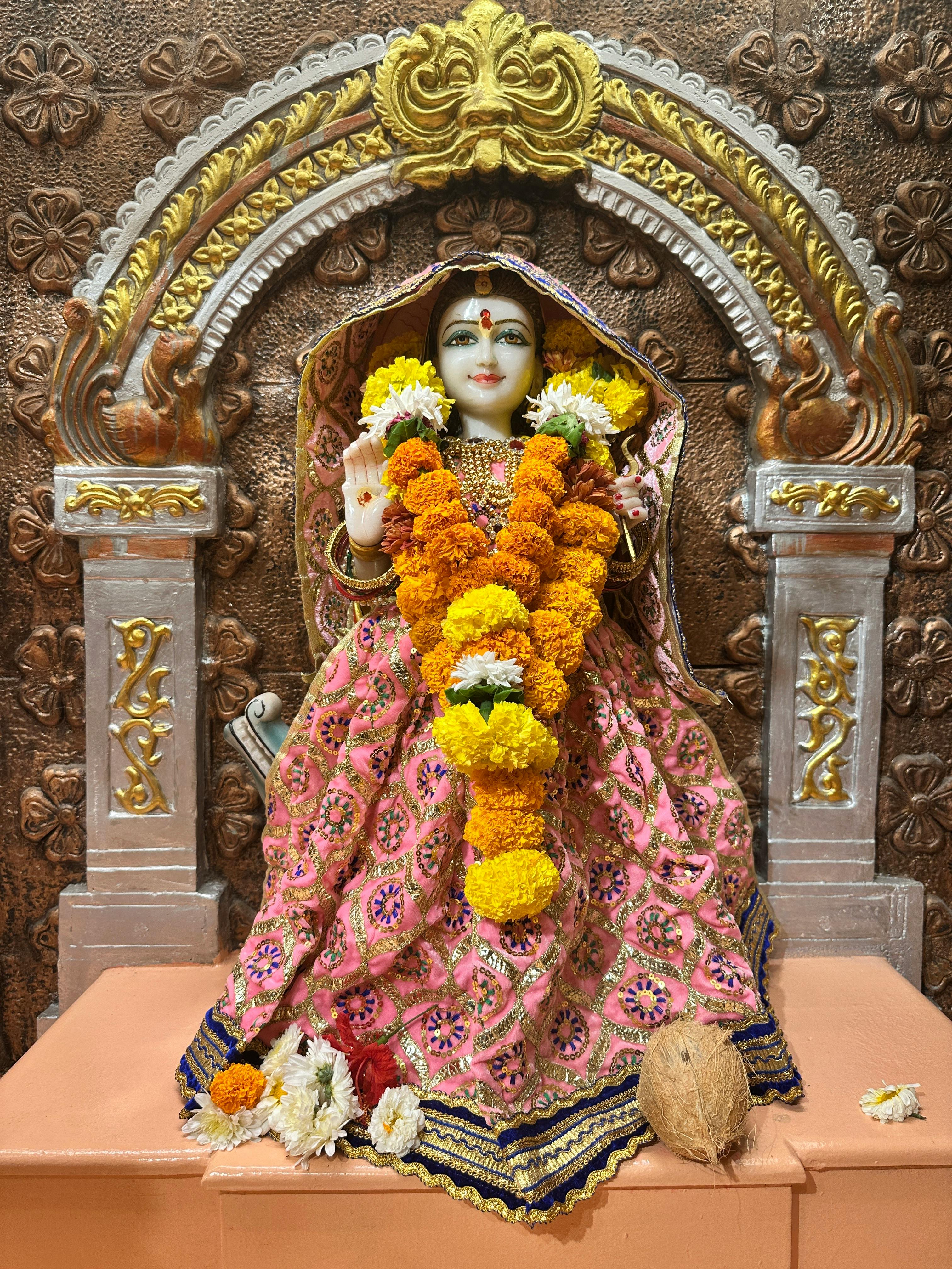 Beautifully decorated statue of a goddess with marigold garlands and intricate carvings.