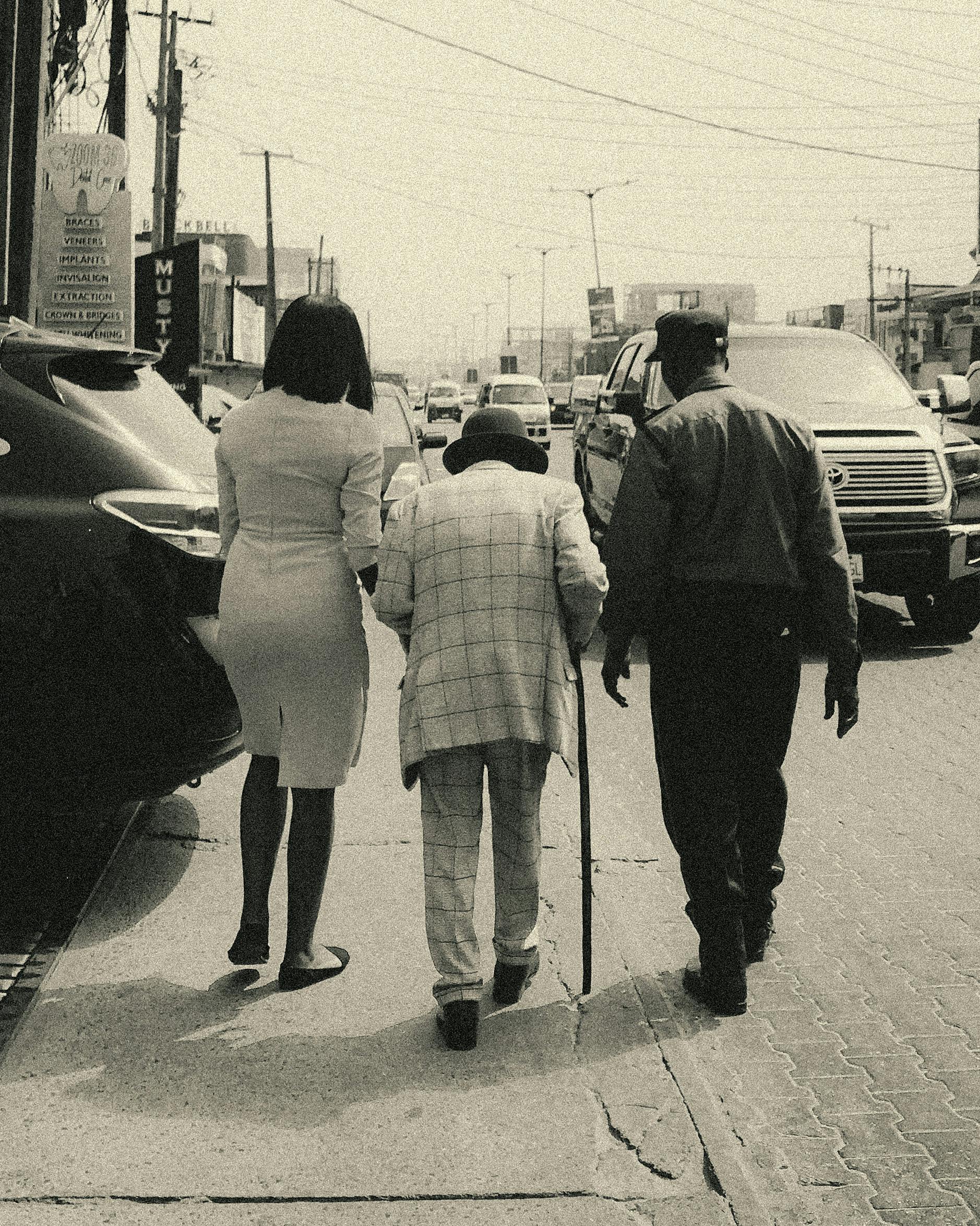 Vintage-style photo of a busy street in Lagos, Nigeria, featuring an elderly man with companions.