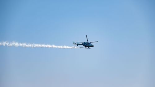 Free A helicopter displaying aerobatics at Bengaluru Airshow against a clear blue sky. Stock Photo