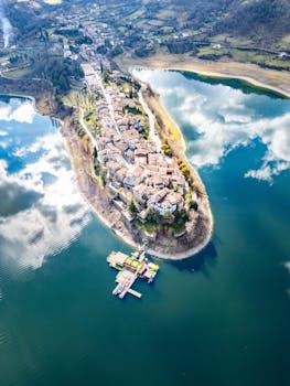 A stunning aerial view of Colle di Tora island surrounded by calm waters and lush hills.