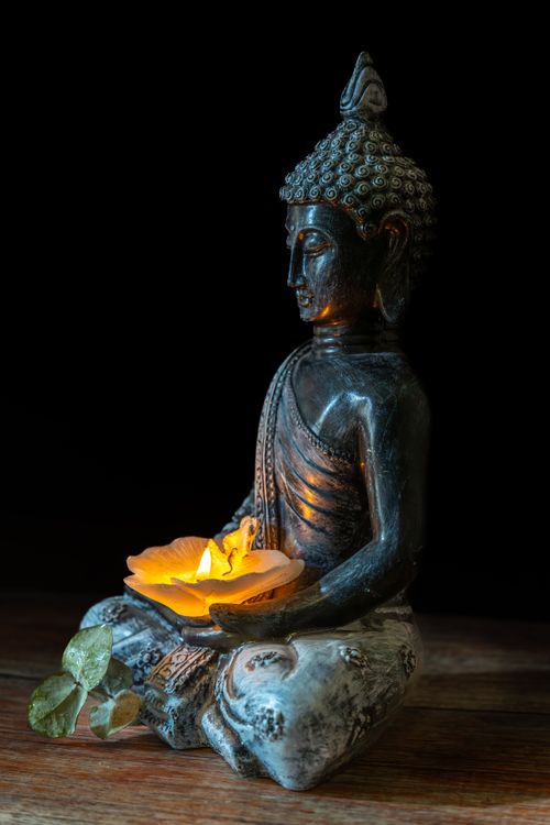 Free A serene Buddha statue holding a candle, symbolizing peace and spirituality. Stock Photo