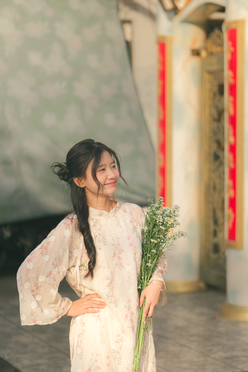 Young Woman in Floral Dress Holding Flowers Outdoors · Free Stock Photo