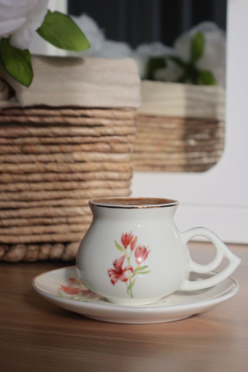 Free Charming floral teacup and saucer on a wooden surface, ideal for tea lovers. Stock Photo