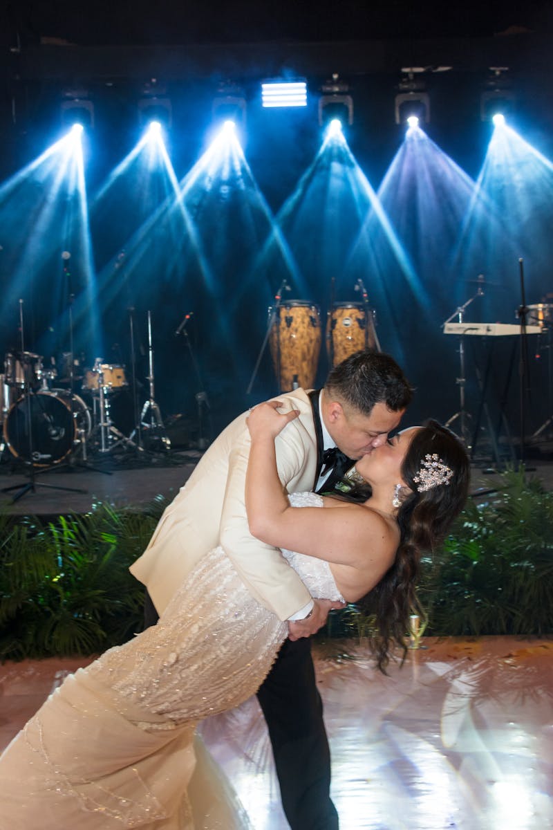 Couple dancing under warm stage lights at wedding reception