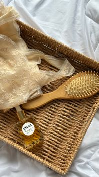Elegant fashion and beauty essentials including lace, oil, and a wooden brush in a rustic basket.