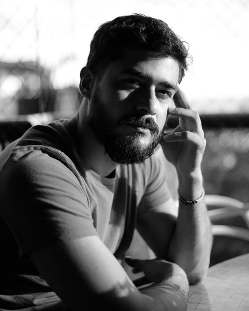 Free A thoughtful man with a beard sitting indoors in a contemplative pose, captured in monochrome. Stock Photo