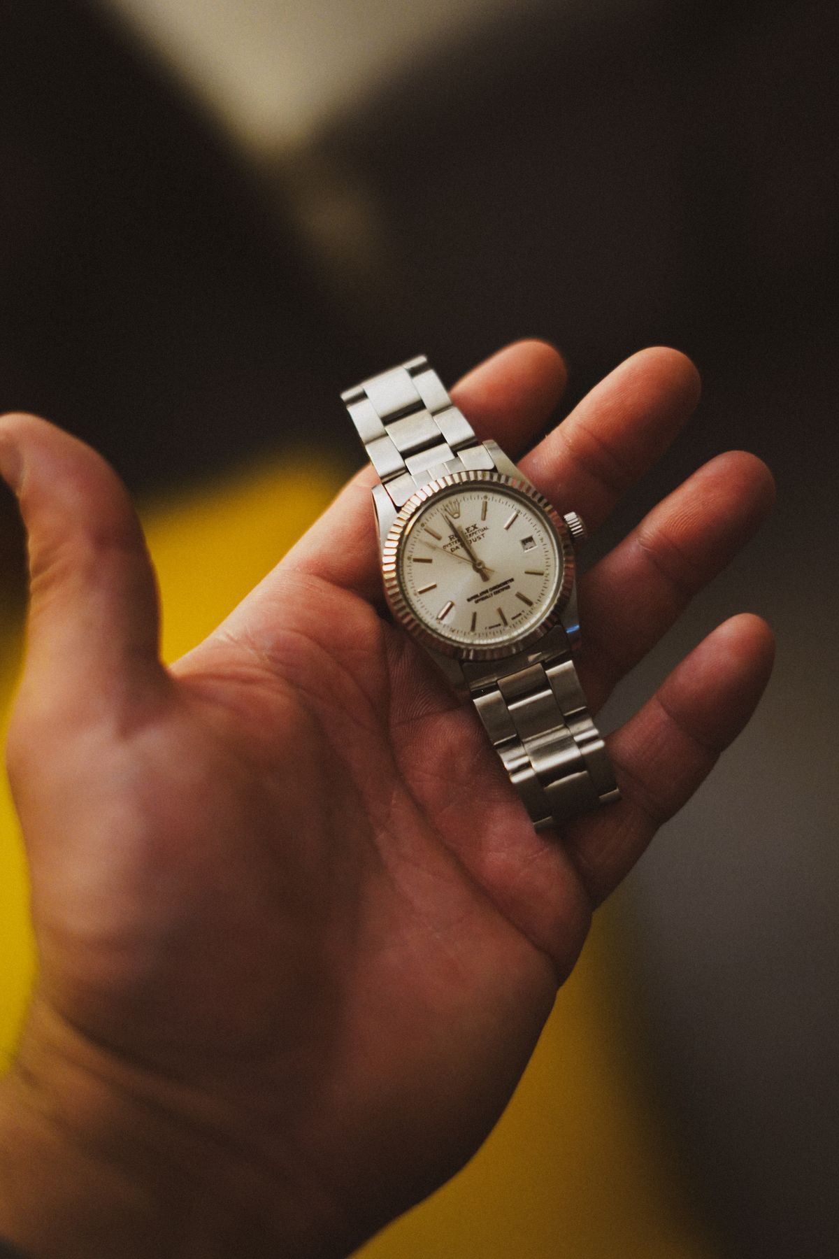 Mano sujetando un reloj vintage con brazalete metálico, mostrando la caja
