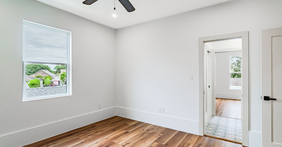 Modern light-filled room with hardwood flooring and ceiling fan in New Orleans.