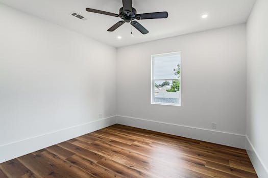 Spacious empty room with hardwood floor and ceiling fan in New Orleans, ideal for real estate listings.