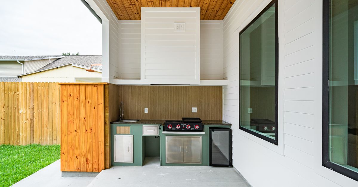 Sleek outdoor kitchen setup with BBQ and fridge in New Orleans backyard.
