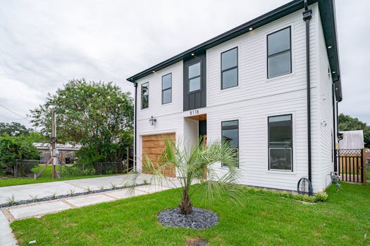 Modern two-story house in New Orleans with a lush green lawn and contemporary design.