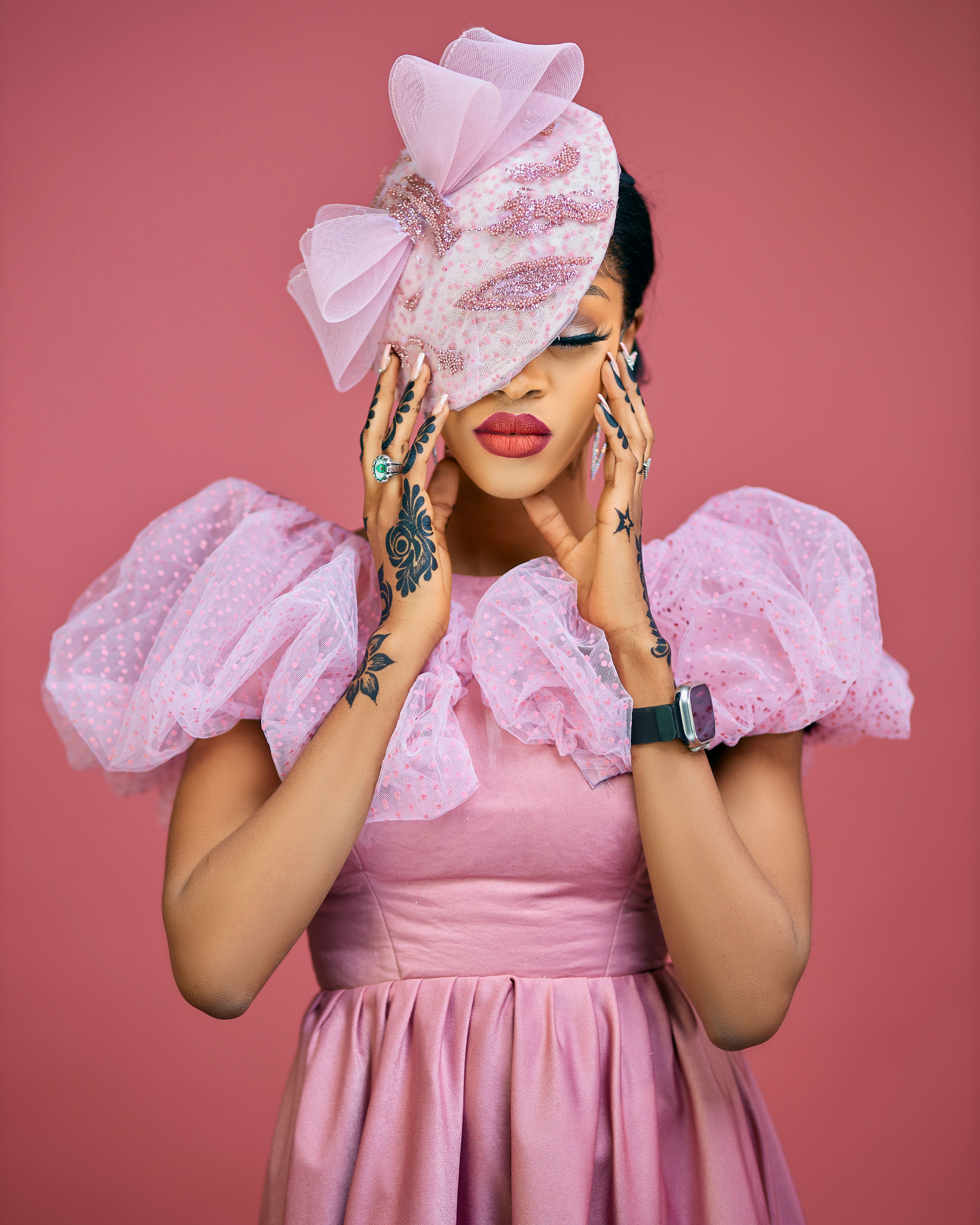 Stylish adult in pink dress and headpiece in studio portrait. Modern elegance and fashion.