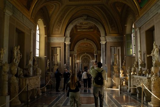 Visitors admire the ancient sculptures in a majestic hallway at the Vatican Museums.