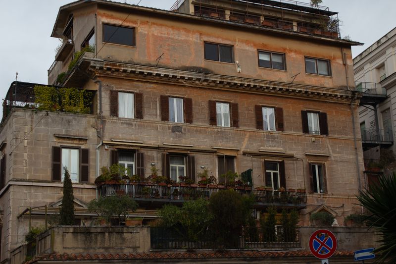 Clădire istorică italiană cu balcoane și vegetație