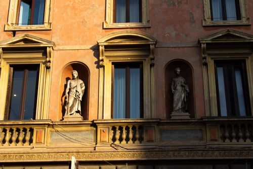 Free Facade with classical sculptures and windows in Rome, Italy, bathed in warm sunlight. Stock Photo
