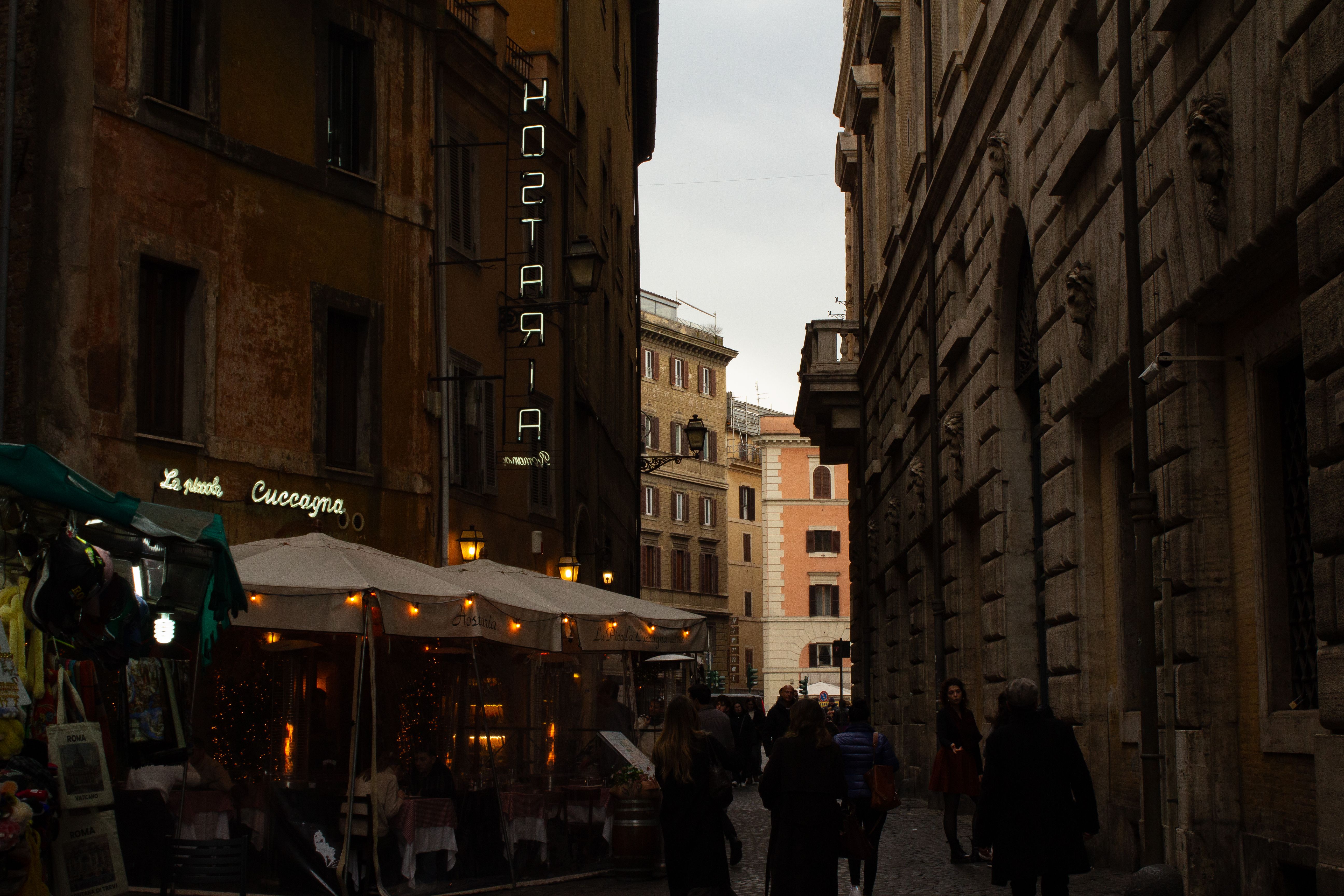 Cozy street in Italy with restaurants and people, evening ambiance.