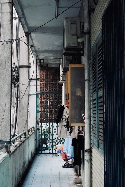 Free A narrow urban corridor with hanging laundry and air conditioning units. Stock Photo