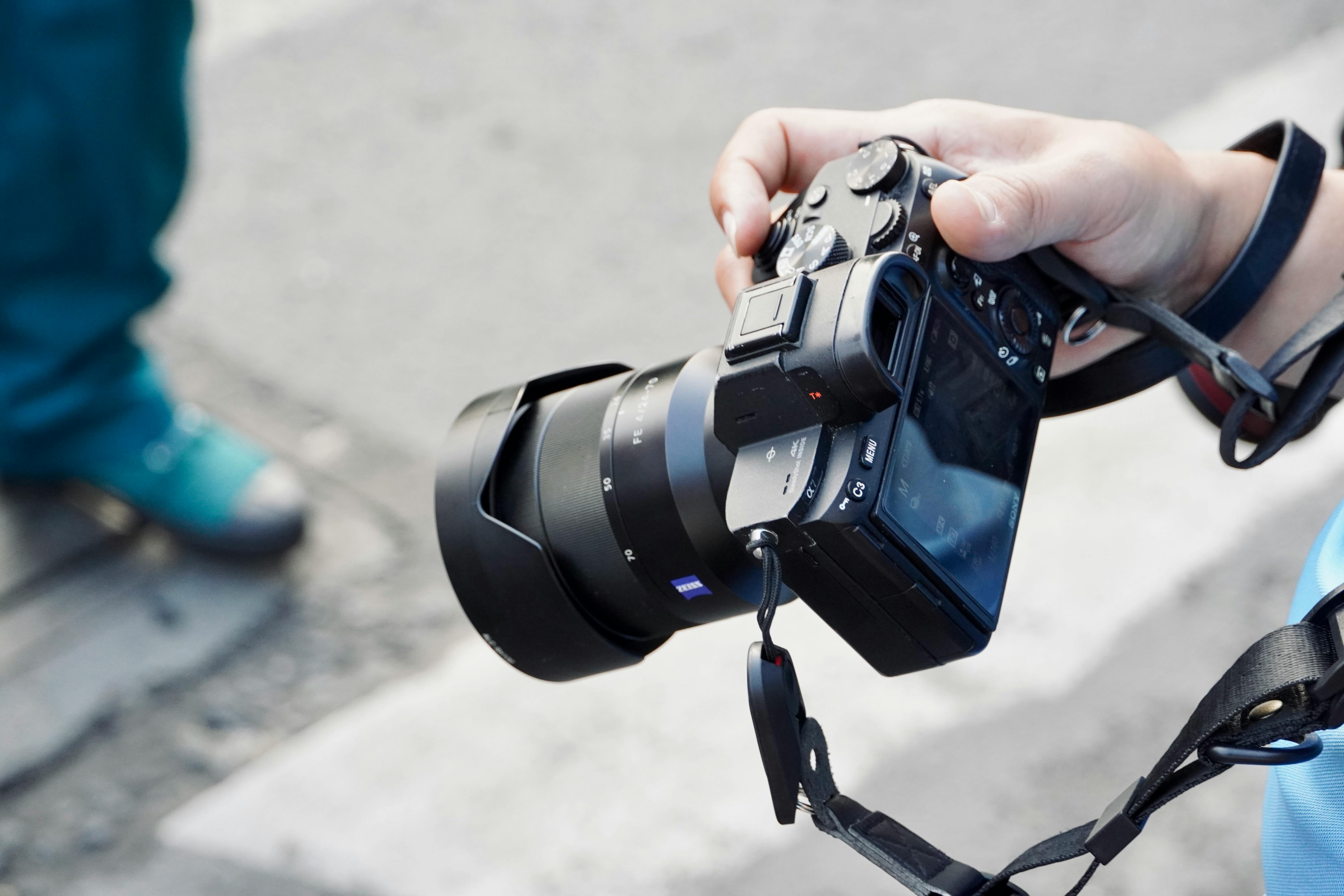 Câmera mirrorless com objetiva pancake montada sendo segurada em contexto de fotografia de rua