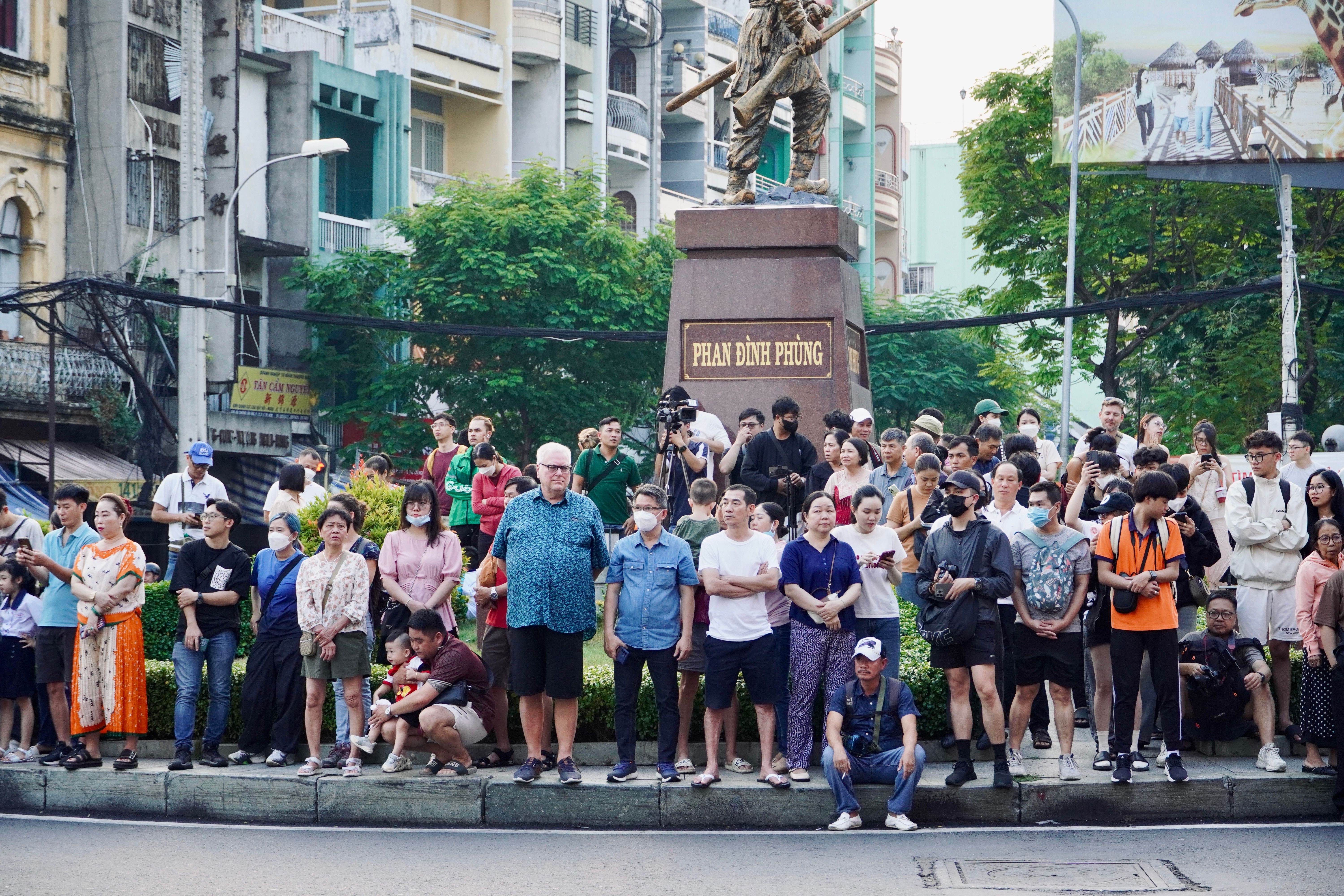 Người dân đứng sau vạch an toàn ghi chú thời gian hoạt động bất thường bằng điện thoại, không tiếp cận hàng rào