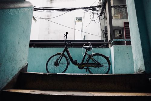 Free A lone bicycle rests against a blue wall in a city alleyway, offering a glimpse into urban life. Stock Photo