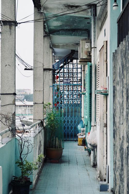 Free A narrow urban alley featuring blue gates, potted plants, and architectural details. Stock Photo