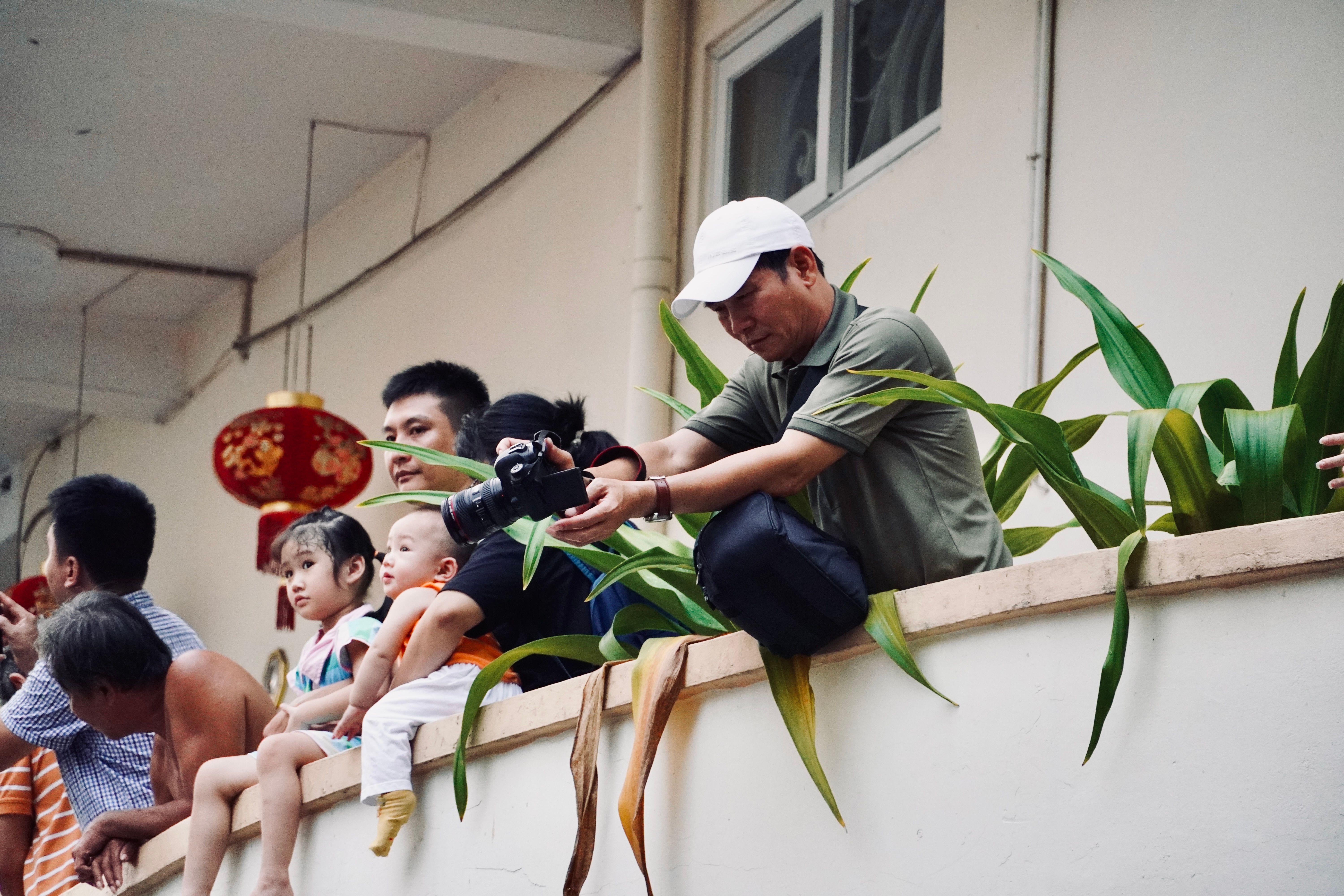 People of various ages watching an event from a balcony, showcasing diverse expressions.