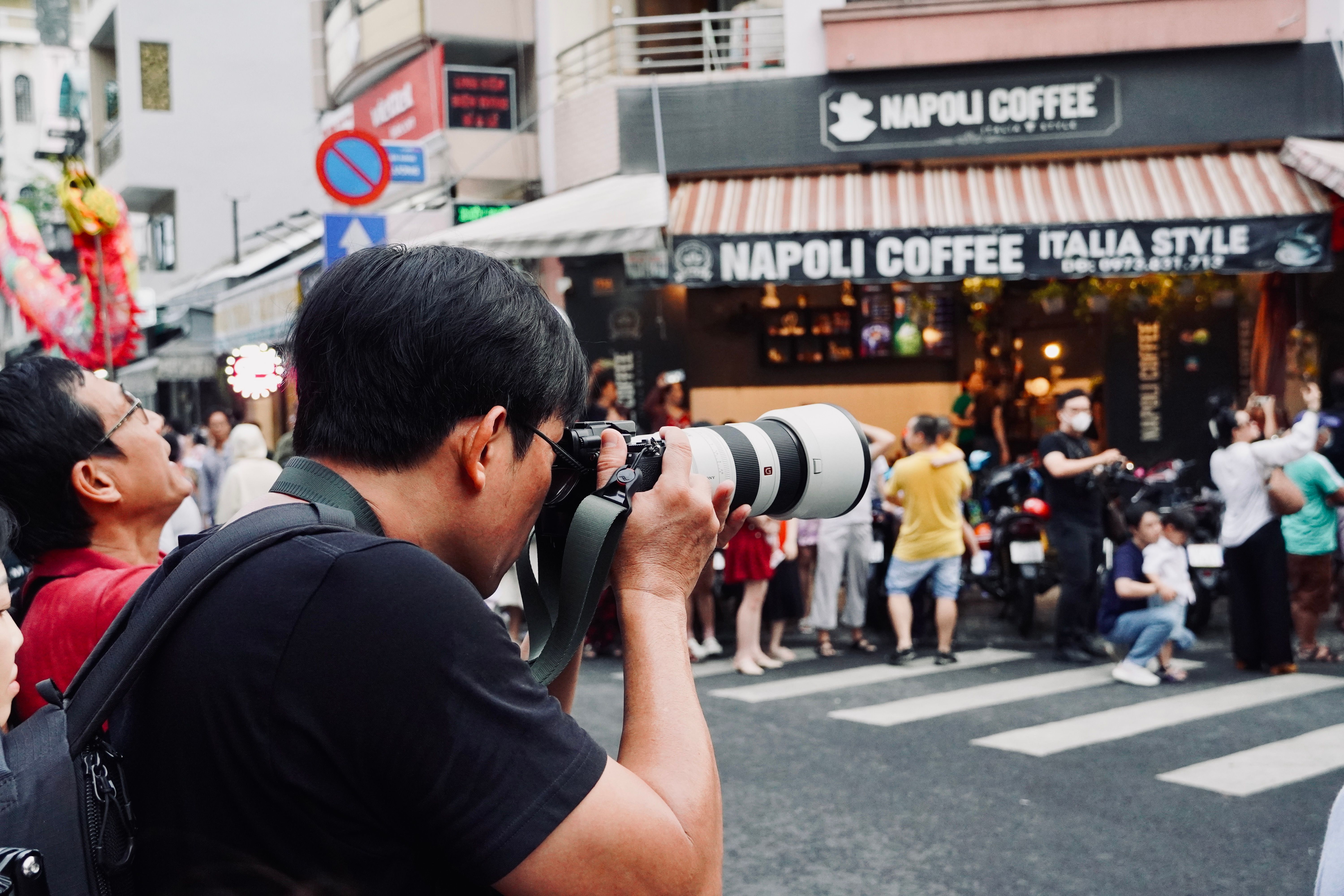 Urban street photographer capturing crowd outside a coffee shop.
