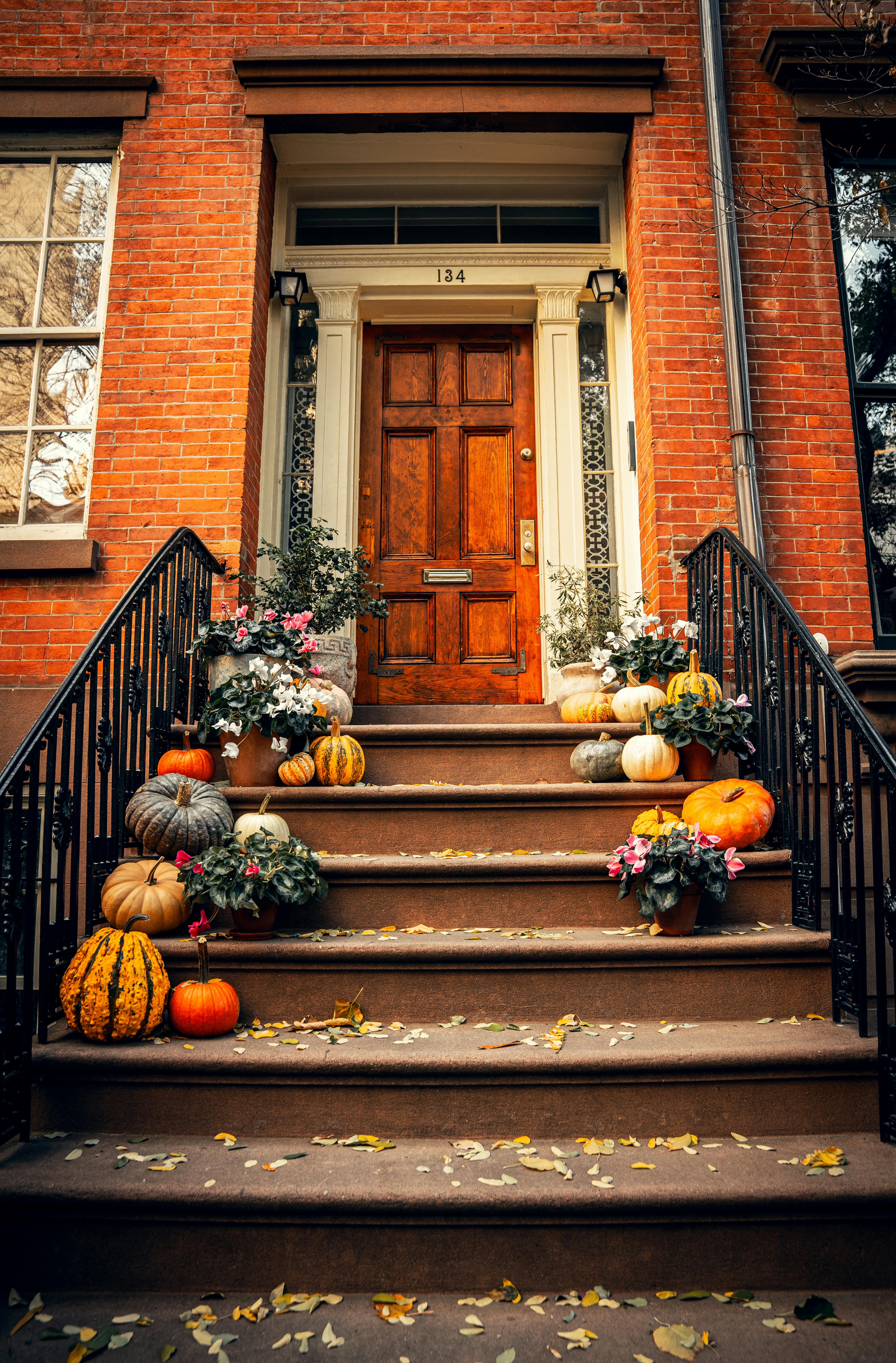 Charming brownstone entrance in New York City adorned with autumn pumpkins and foliage.