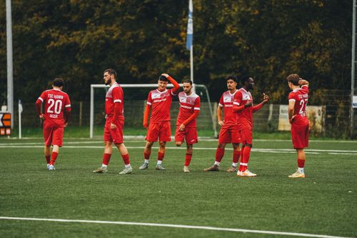 Free Amateur soccer team in red uniforms gathering on a green field during daytime. Stock Photo