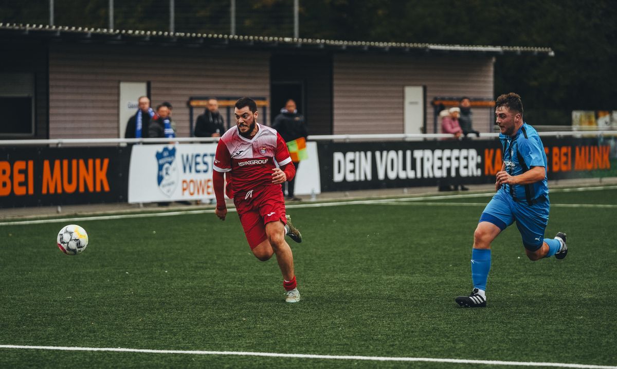 Çim sahada futbol topu üzerine eğilen iki futbolcu