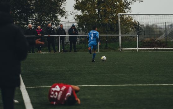 A soccer player in blue runs the field as spectators watch closely during an intense match.