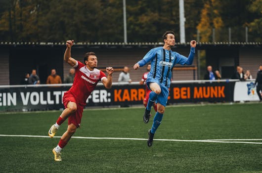Two soccer players in action during a competitive match on a green field.