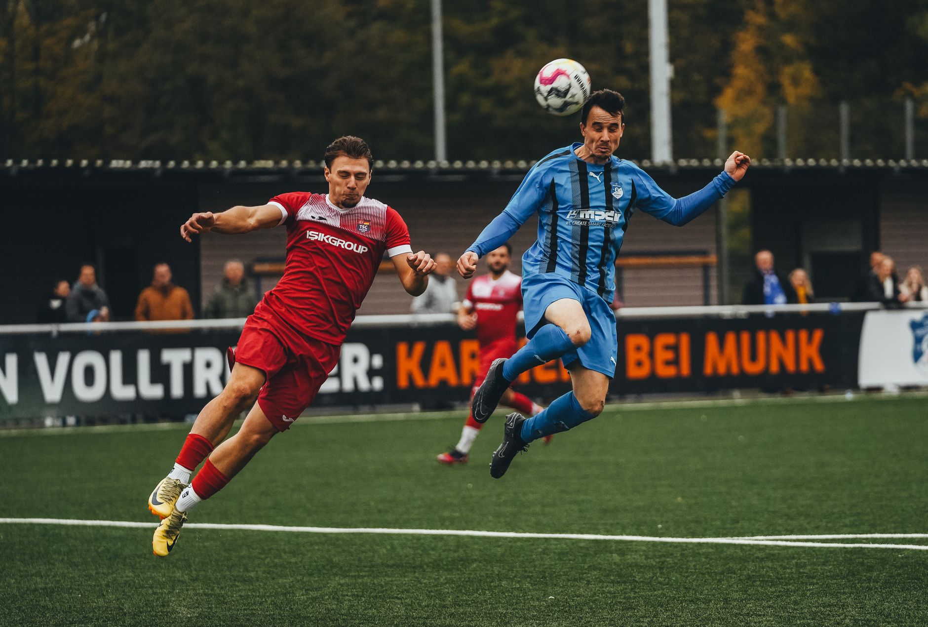 Dynamic photo of two soccer players mid-air during a competitive match.