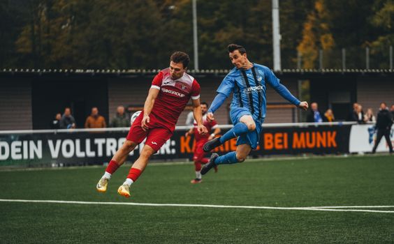 Two soccer players compete fiercely during a match on a green field.
