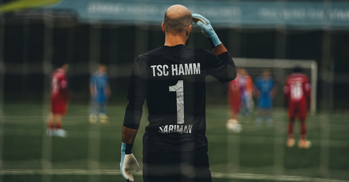 A soccer goalkeeper stands ready for a penalty kick on a field.
